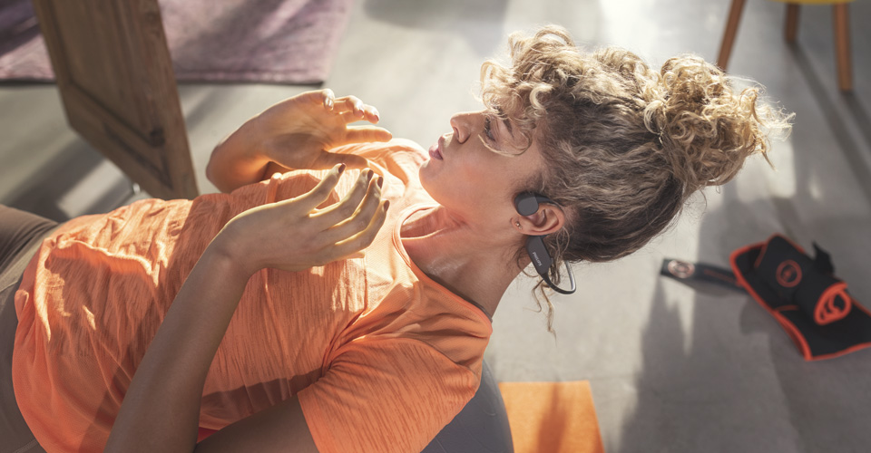 Kapalı alanda egzersiz yaparken a&ccedil;ık kulak tasarımlı kulaklık kullanan sporcu