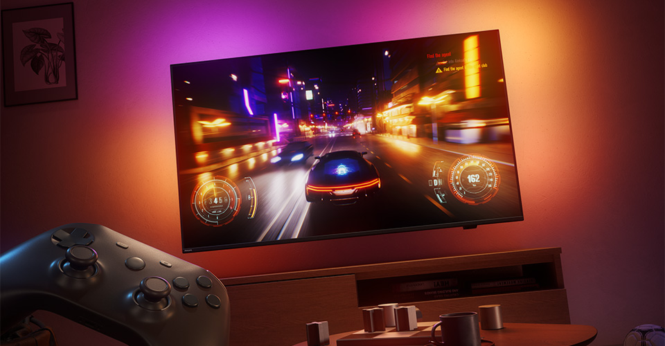 Loş ışıklı bir odada Philips Ambilight TV'de yarış video oyunu g&ouml;steriliyor