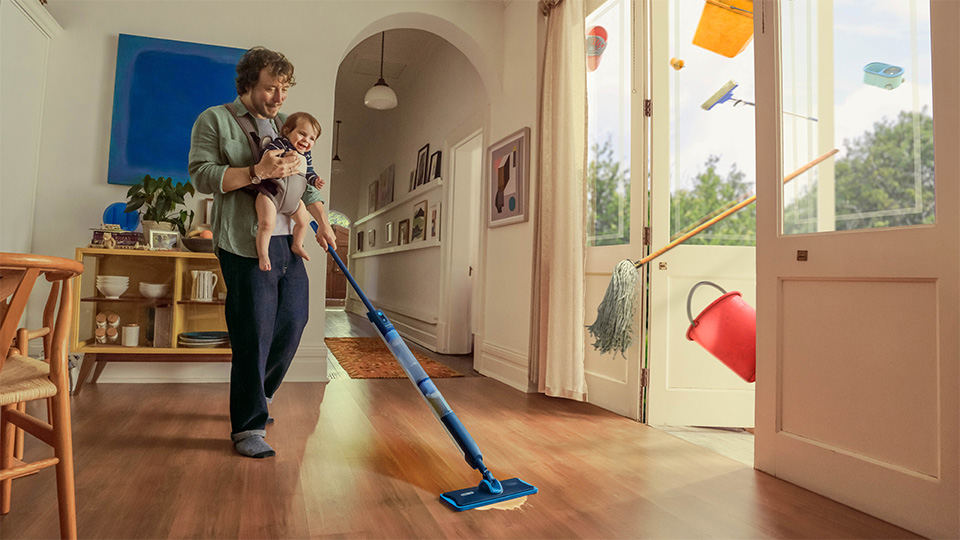 bebeğini taşıyan ve zemini temizlemek i&ccedil;in Philips OneUp Elektrikli Paspas kullanan bir adam